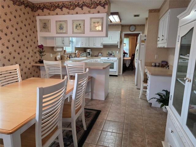 579 Rockingham Rd, Orange Park, FL 32073 - kitchen featuring white appliances, wallpapered walls, light countertops, white cabinets, and a sink