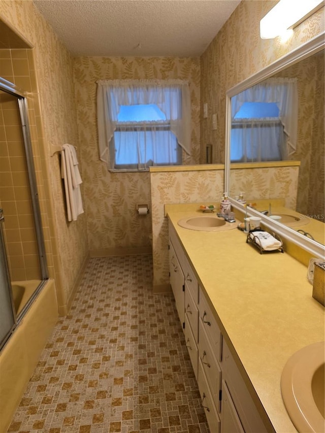 579 Rockingham Rd, Orange Park, FL 32073 - full bath with wallpapered walls, a textured ceiling, double vanity, and bath / shower combo with glass door