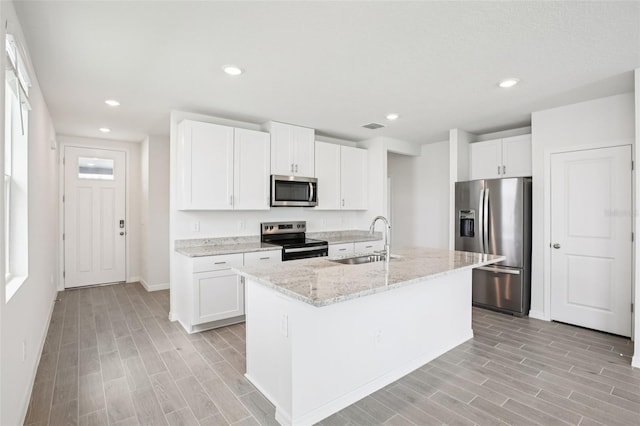 1828 Brekey Way, Zephyrhills, FL 33541 - kitchen featuring appliances with stainless steel finishes, light wood-style flooring, light stone countertops, white cabinetry, and recessed lighting