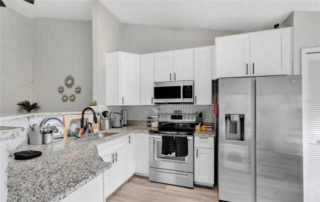 9616 River Walk Ct, Orlando, FL 32825 - kitchen featuring appliances with stainless steel finishes, a sink, lofted ceiling, decorative backsplash, and light stone countertops