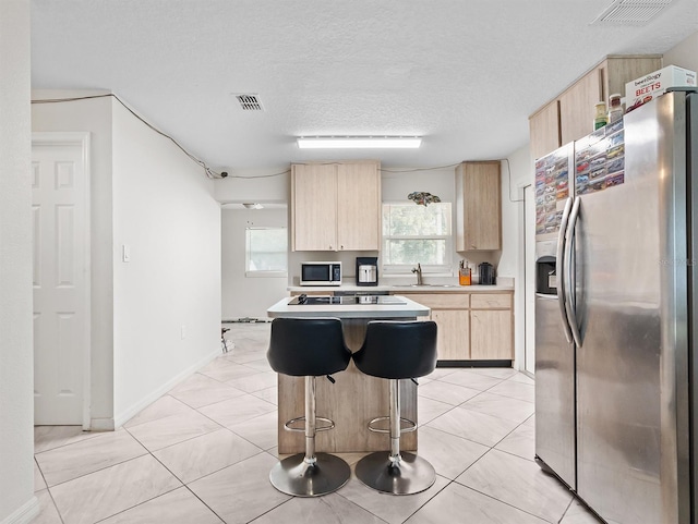 4546 Malibu St, Orlando, FL 32811 - kitchen with stainless steel appliances, light brown cabinets, light countertops, a textured ceiling, and a breakfast bar