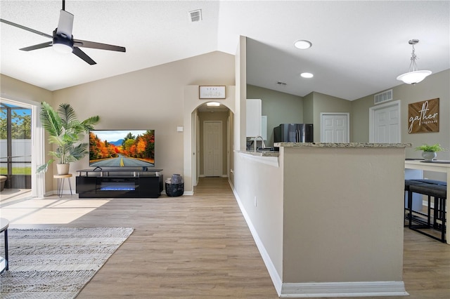 2406 Placid Way, Kissimmee, FL 34758 - living room with vaulted ceiling, ceiling fan, light wood-style floors, arched walkways, and baseboards