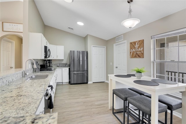 2406 Placid Way, Kissimmee, FL 34758 - kitchen with freestanding refrigerator, a sink, lofted ceiling, arched walkways, and light stone countertops