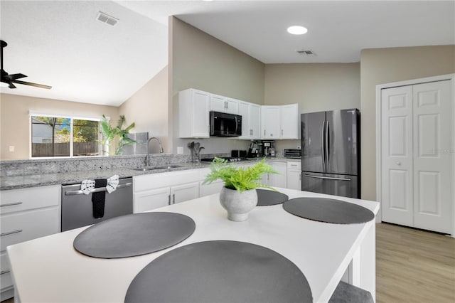 2406 Placid Way, Kissimmee, FL 34758 - kitchen featuring stainless steel appliances, a sink, white cabinets, light wood-style floors, and high vaulted ceiling