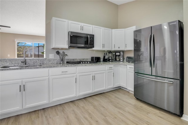 2406 Placid Way, Kissimmee, FL 34758 - kitchen with stainless steel appliances, a sink, white cabinets, light stone countertops, and light wood-style flooring
