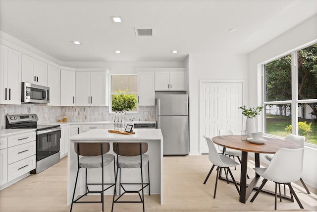 14927 Faversham Cir, Orlando, FL 32826 - kitchen with appliances with stainless steel finishes, plenty of natural light, a breakfast bar, a kitchen island, and recessed lighting