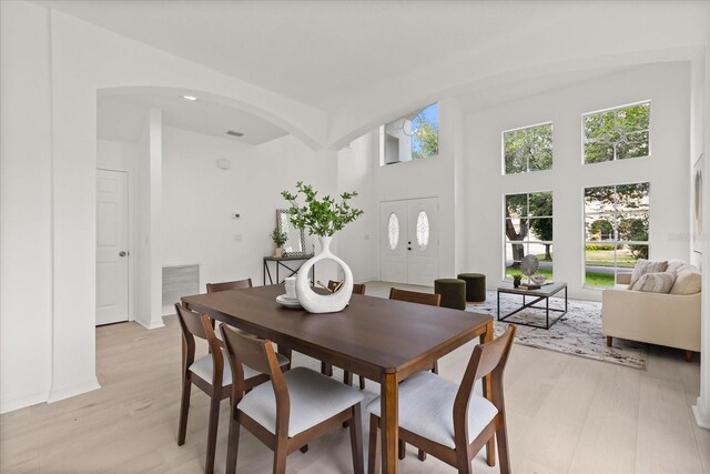 14927 Faversham Cir, Orlando, FL 32826 - dining space featuring arched walkways, light wood-style flooring, and a towering ceiling