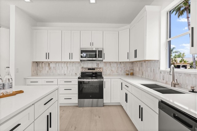 14927 Faversham Cir, Orlando, FL 32826 - kitchen featuring appliances with stainless steel finishes, a sink, white cabinetry, and light wood finished floors