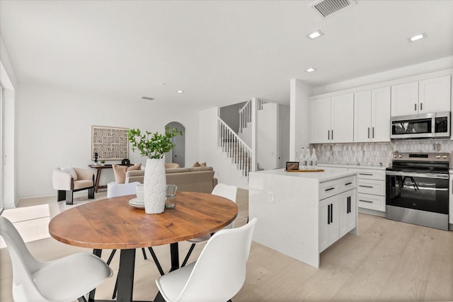 14927 Faversham Cir, Orlando, FL 32826 - kitchen with stainless steel appliances, backsplash, white cabinets, light wood-style floors, and light countertops