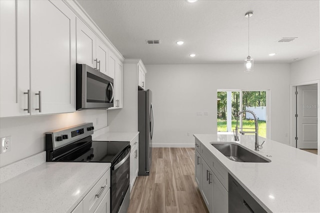 3863 W Galleon St, Dunnellon, FL 34433 - kitchen featuring stainless steel appliances, a sink, light wood-style floors, white cabinets, and light stone countertops
