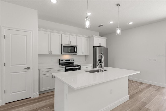 3863 W Galleon St, Dunnellon, FL 34433 - kitchen featuring stainless steel appliances, recessed lighting, white cabinets, light wood-type flooring, and a center island with sink