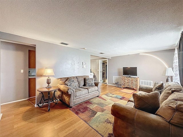5415 Riddle Rd, Holiday, FL 34690 - living room featuring light wood-style flooring, a textured ceiling, and baseboards