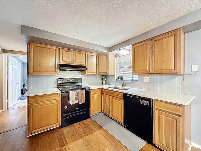 5415 Riddle Rd, Holiday, FL 34690 - kitchen featuring black appliances, a sink, under cabinet range hood, light wood-style flooring, and tasteful backsplash