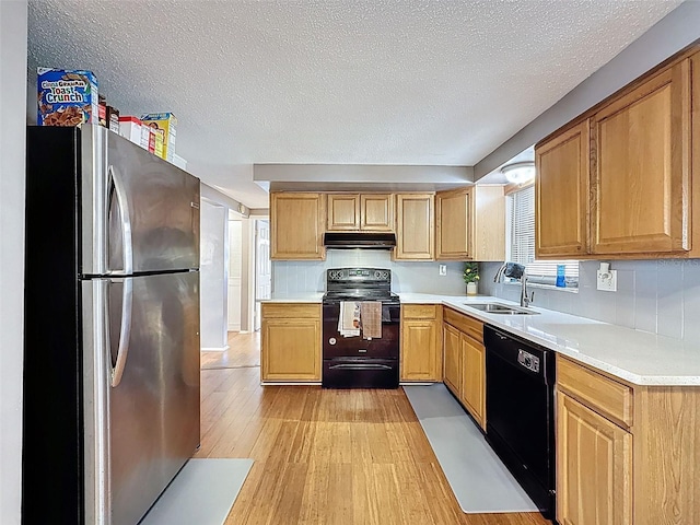 5415 Riddle Rd, Holiday, FL 34690 - kitchen with black appliances, under cabinet range hood, a sink, light countertops, and light wood-style floors
