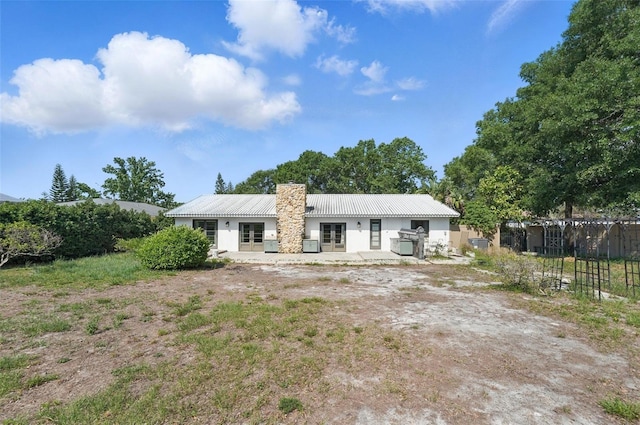 6327 Ridgeberry Dr, Orlando, FL 32819 - back of house with french doors, a metal roof, stucco siding, and a chimney