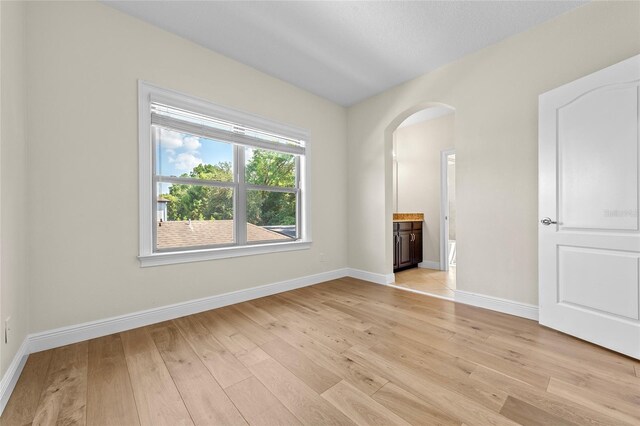 808 Sherbourne Cir, Lake Mary, FL 32746 - empty room with arched walkways, light wood-type flooring, and baseboards