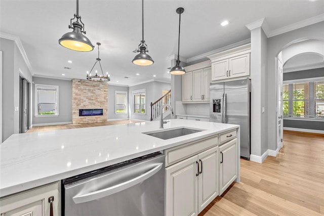808 Sherbourne Cir, Lake Mary, FL 32746 - kitchen featuring appliances with stainless steel finishes, a sink, ornamental molding, arched walkways, and hanging light fixtures