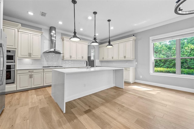 808 Sherbourne Cir, Lake Mary, FL 32746 - kitchen with wall chimney exhaust hood, stovetop, light countertops, an island with sink, and light wood finished floors