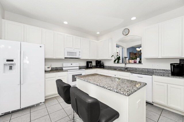 2209 Crofton Ave, Davenport, FL 33837 - kitchen with white appliances, light tile patterned flooring, a kitchen island, a sink, and white cabinets