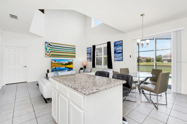 2209 Crofton Ave, Davenport, FL 33837 - kitchen with light tile patterned flooring, open floor plan, a chandelier, white cabinets, and high vaulted ceiling