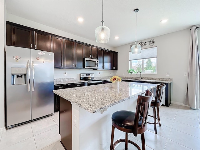 15865 Bradicks Ct, Clermont, FL 34711 - kitchen with stainless steel appliances, dark brown cabinetry, light stone counters, a kitchen island, and decorative light fixtures