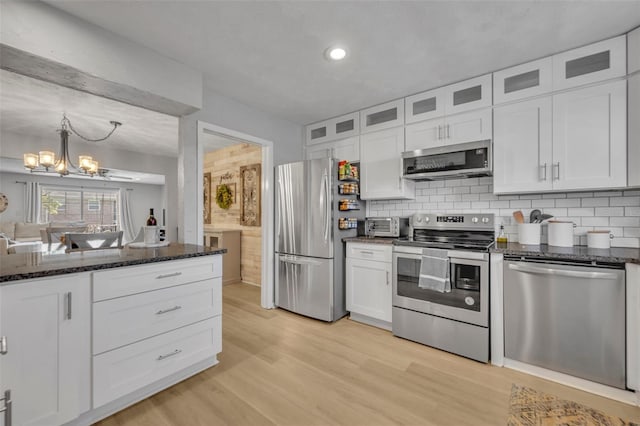 4306 Lake Underhill Rd Unit C, Orlando, FL 32803 - kitchen featuring stainless steel appliances, a chandelier, light wood-style flooring, white cabinetry, and glass insert cabinets