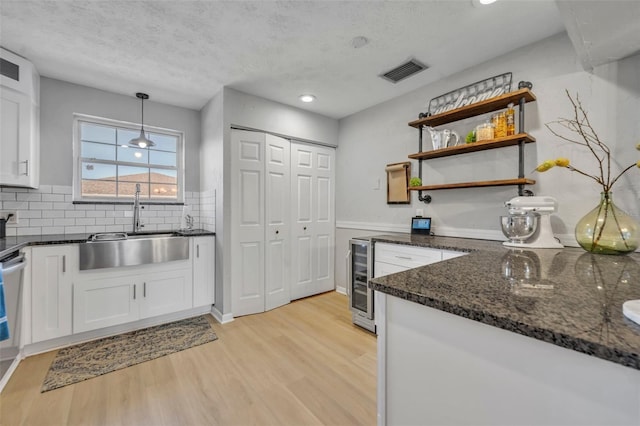 4306 Lake Underhill Rd Unit C, Orlando, FL 32803 - kitchen with beverage cooler, a sink, white cabinetry, light wood-style floors, and dark stone countertops