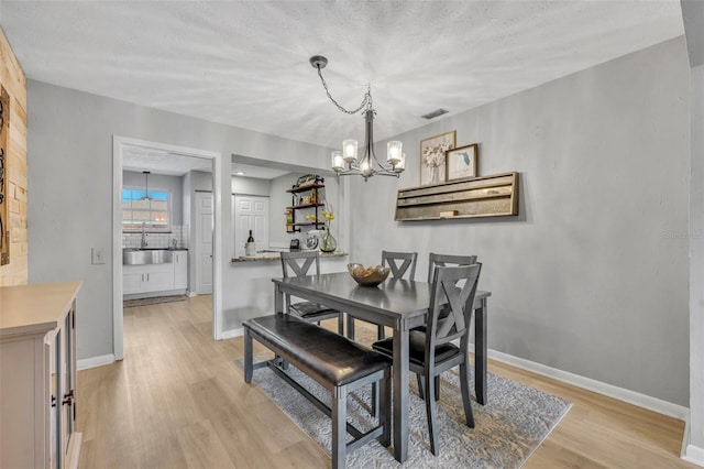 4306 Lake Underhill Rd Unit C, Orlando, FL 32803 - dining area with a chandelier, light wood-type flooring, baseboards, and a textured ceiling
