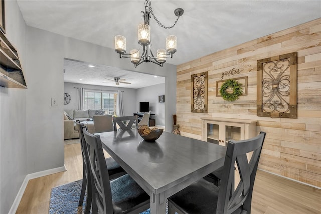 4306 Lake Underhill Rd Unit C, Orlando, FL 32803 - dining area with wood walls, a chandelier, light wood-style flooring, baseboards, and an accent wall