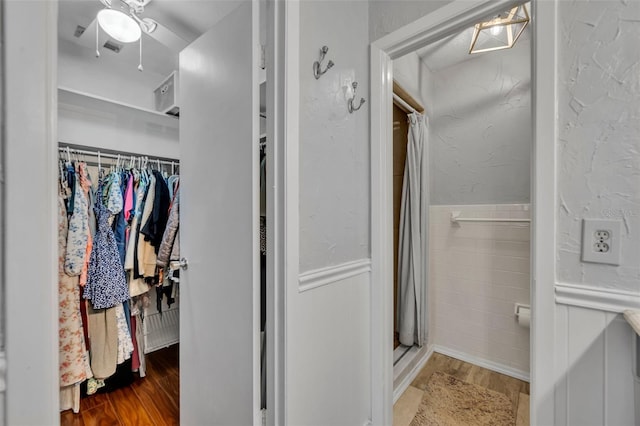 4306 Lake Underhill Rd Unit C, Orlando, FL 32803 - full bathroom featuring wood finished floors, a stall shower, a spacious closet, ceiling fan, and wainscoting