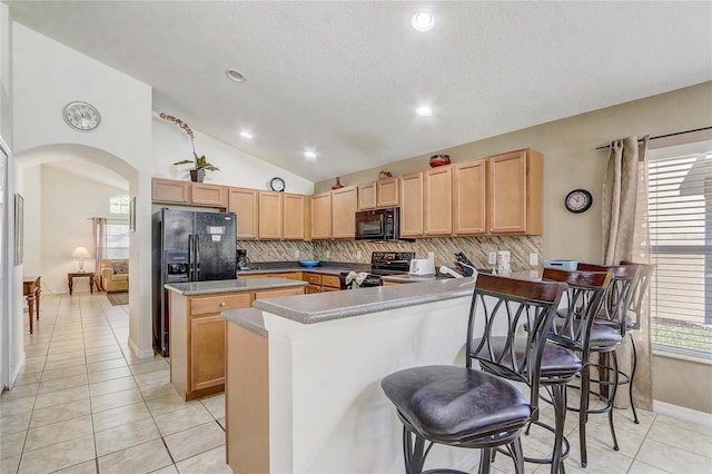 927 Orange Cosmos Blvd, Davenport, FL 33837 - kitchen with black appliances, tasteful backsplash, a center island, arched walkways, and light tile patterned flooring