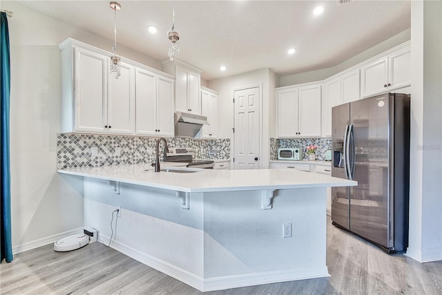 1147 Wildmeadow Run, Winter Park, FL 32792 - kitchen with stainless steel appliances, a sink, a peninsula, under cabinet range hood, and light countertops