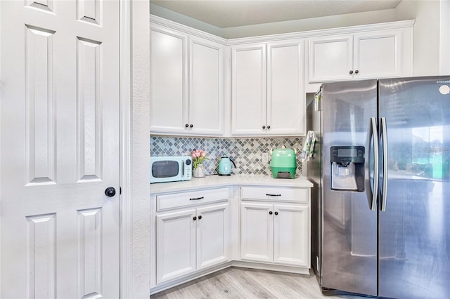 1147 Wildmeadow Run, Winter Park, FL 32792 - kitchen featuring stainless steel fridge, white microwave, light countertops, light wood-style floors, and white cabinetry