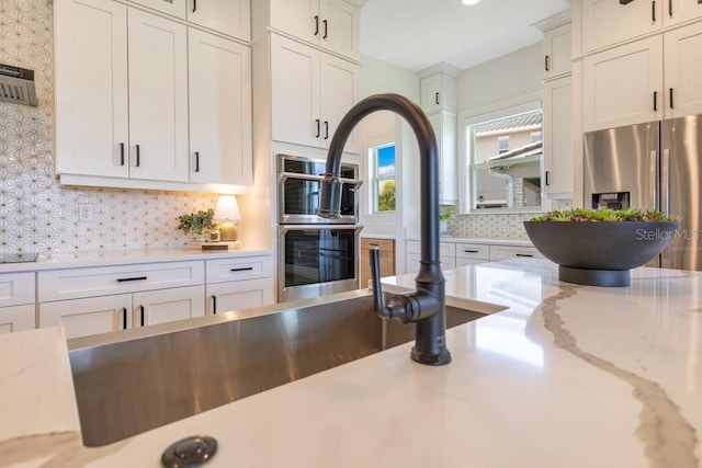 13791 Abberwick Dr, Orlando, FL 32832 - kitchen featuring appliances with stainless steel finishes, decorative backsplash, light stone counters, and white cabinetry