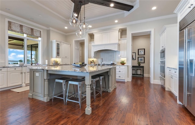 10845 Bayshore Dr, Windermere, FL 34786 - kitchen featuring a kitchen island with sink, built in refrigerator, white cabinetry, dark wood-style floors, and a kitchen bar