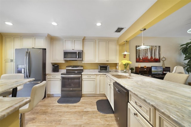 1074 Kensington Park Ct Unit 101, Altamonte Springs, FL 32714 - kitchen featuring appliances with stainless steel finishes, cream cabinetry, a sink, hanging light fixtures, and recessed lighting