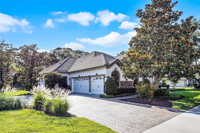 190 Osprey Hammock Trl, Sanford, FL 32771 - view of front facade with a garage, stucco siding, a tile roof, decorative driveway, and stone siding