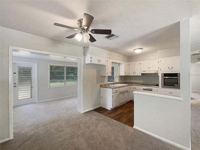300 Ave E SE, Winter Haven, FL 33880 - kitchen with oven, a sink, dark carpet, ceiling fan, and white cabinets