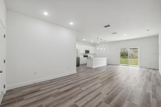 16904 SW 30th Avenue Rd, Ocala, FL 34473 - unfurnished living room with light wood-type flooring, recessed lighting, baseboards, and a sink