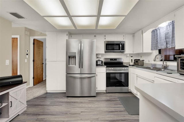 409 Jumper Dr S, Bushnell, FL 33513 - kitchen with stainless steel appliances, wood finished floors, a sink, and white cabinets