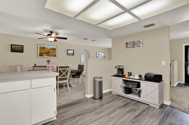 409 Jumper Dr S, Bushnell, FL 33513 - kitchen featuring arched walkways, light wood-style floors, white cabinetry, a ceiling fan, and baseboards