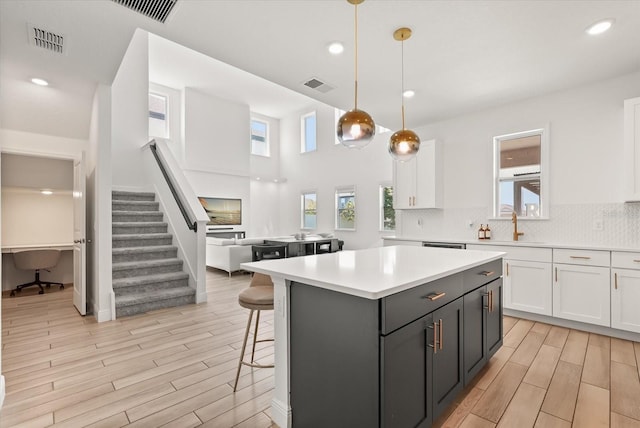 5700 Iron Brand Rd, Saint Cloud, FL 34771 - kitchen with white cabinets, light wood-type flooring, light countertops, a center island, and recessed lighting