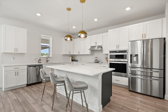 5700 Iron Brand Rd, Saint Cloud, FL 34771 - kitchen featuring appliances with stainless steel finishes, under cabinet range hood, light wood finished floors, light countertops, and white cabinets