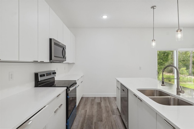 6062 SW 154th Pl, Ocala, FL 34473 - kitchen with stainless steel appliances, a sink, white cabinets, dark wood finished floors, and light countertops