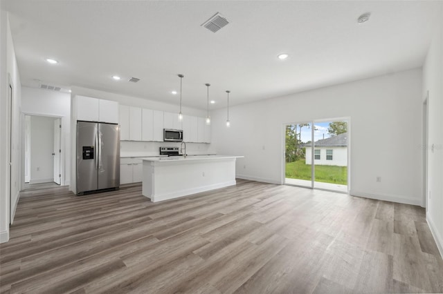 6062 SW 154th Pl, Ocala, FL 34473 - kitchen with stainless steel appliances, recessed lighting, white cabinets, open floor plan, and light wood-style floors
