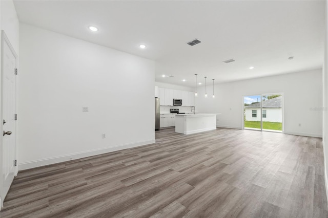 6062 SW 154th Pl, Ocala, FL 34473 - unfurnished living room with light wood-type flooring, recessed lighting, a sink, and baseboards