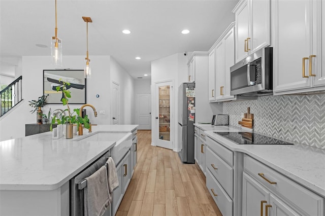 1425 Paget Cv, Sanford, FL 32771 - kitchen featuring stainless steel appliances, light wood-style floors, a center island with sink, decorative backsplash, and a sink
