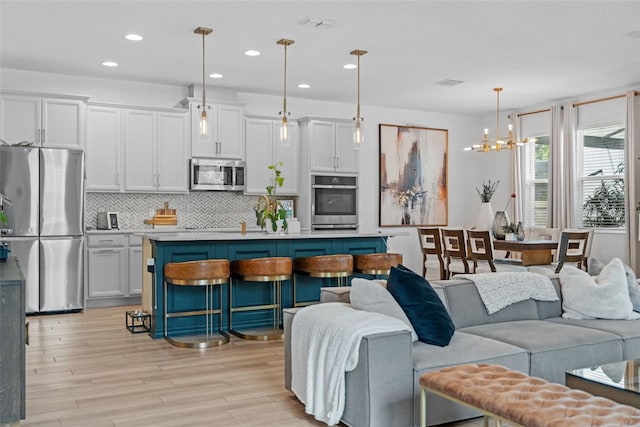 1425 Paget Cv, Sanford, FL 32771 - kitchen featuring stainless steel appliances, backsplash, light wood-style flooring, open floor plan, and light countertops