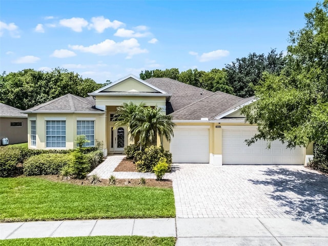 2026 Winding Oaks Dr, Orlando, FL 32825 - view of front of house with decorative driveway, a garage, stucco siding, a front yard, and a shingled roof