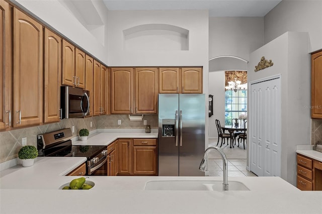2026 Winding Oaks Dr, Orlando, FL 32825 - kitchen featuring stainless steel appliances, a sink, a chandelier, light countertops, and a high ceiling